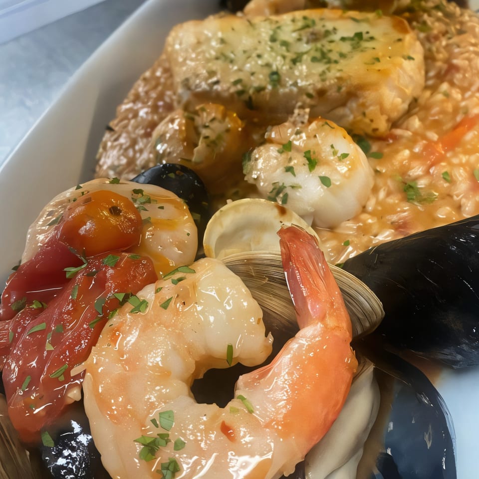 Close-up of Alfredo's seafood risotto with shrimp, mussels, clams, scallops, and cherry tomatoes.